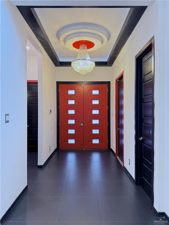 tiled foyer entrance with a tray ceiling and baseboards