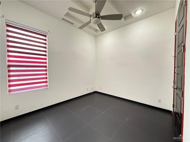 spare room with dark tile patterned floors, ceiling fan, visible vents, and baseboards