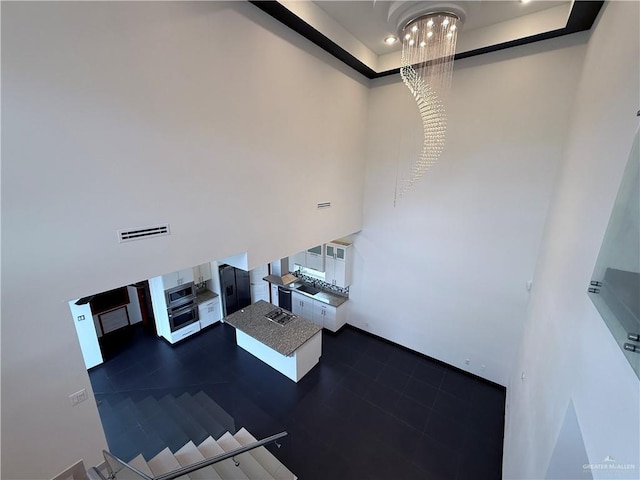 unfurnished living room with a tray ceiling, a high ceiling, and visible vents