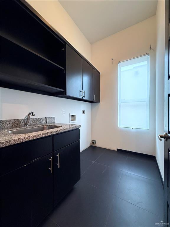 laundry area with washer hookup, cabinet space, hookup for an electric dryer, a sink, and dark tile patterned floors