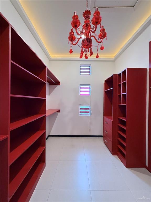 spacious closet with light tile patterned floors and a notable chandelier