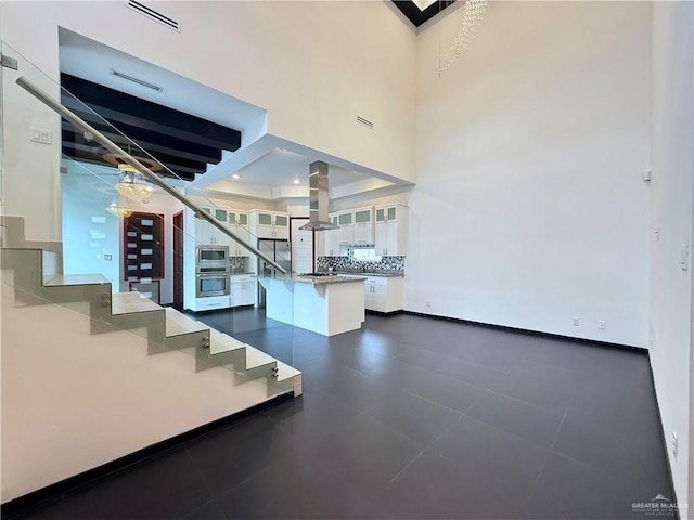 stairs with baseboards, visible vents, and a high ceiling