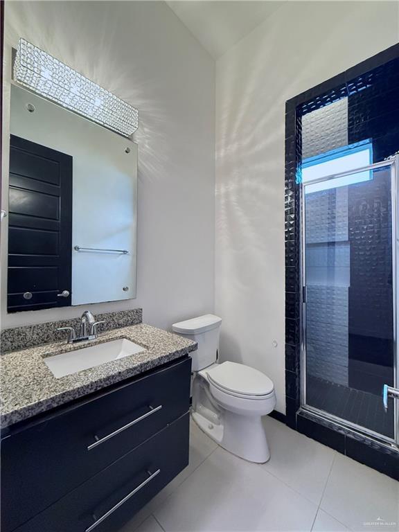 bathroom with toilet, a shower stall, vanity, and tile patterned floors