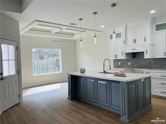 kitchen featuring a kitchen island with sink, decorative backsplash, white cabinets, and a sink