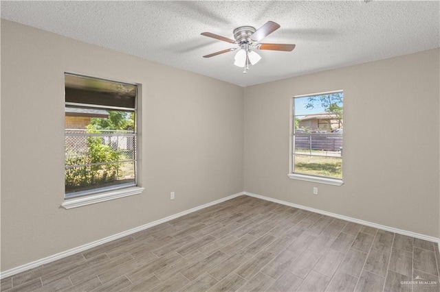 spare room featuring plenty of natural light, a ceiling fan, light wood finished floors, and baseboards