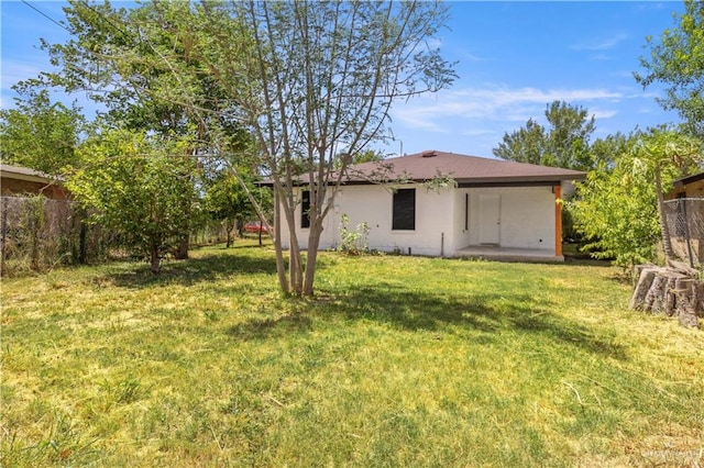 back of property featuring fence and a yard