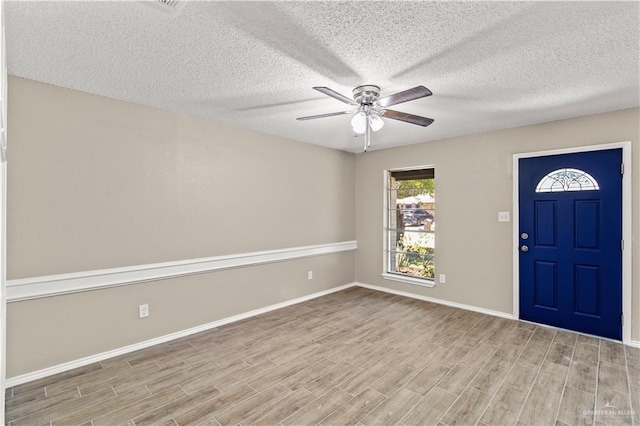 foyer entrance with baseboards, a textured ceiling, ceiling fan, and wood finished floors