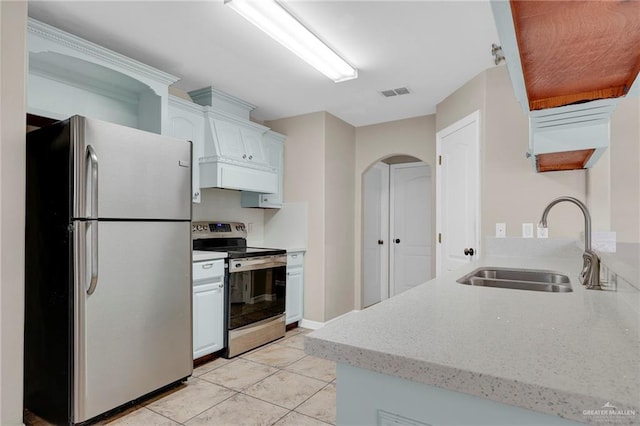 1821 S Petunia Ave, Weslaco, TX 78596 - kitchen featuring appliances with stainless steel finishes, arched walkways, white cabinetry, light tile patterned flooring, and light stone counters