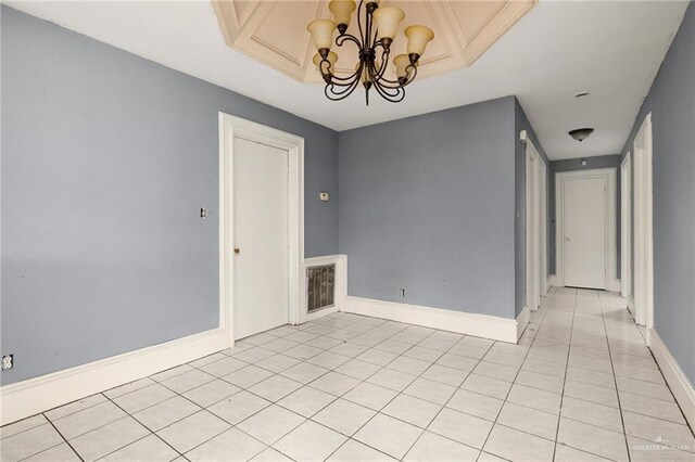 tiled spare room with a chandelier