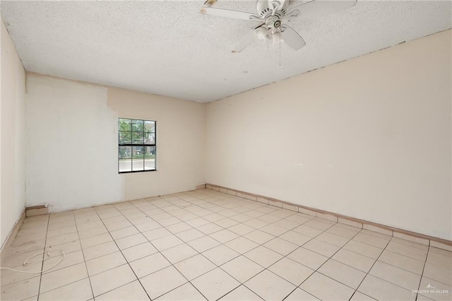 spare room featuring ceiling fan, light tile patterned floors, and a textured ceiling