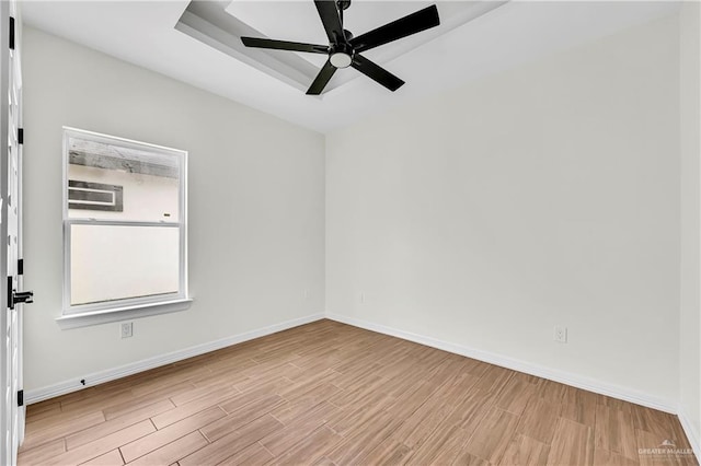 unfurnished room with a tray ceiling, light hardwood / wood-style flooring, and ceiling fan