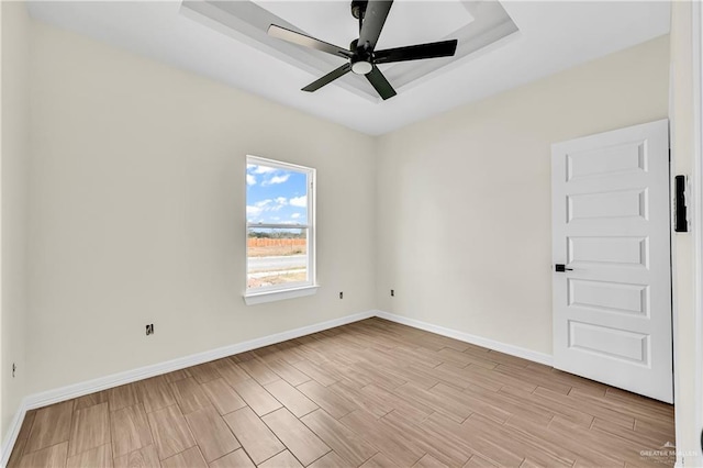 empty room featuring a raised ceiling and ceiling fan