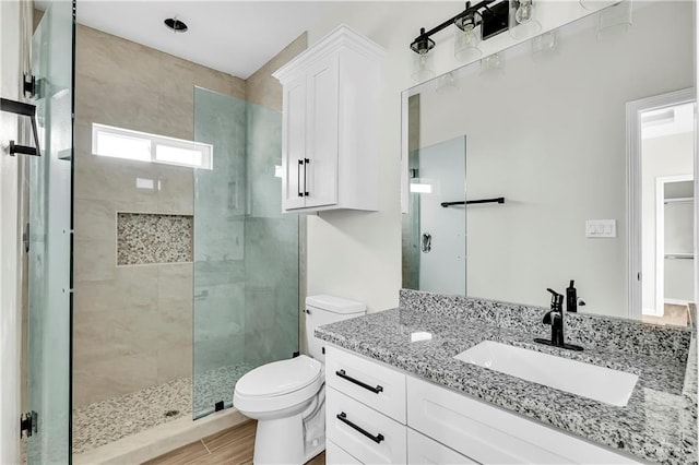 bathroom featuring vanity, hardwood / wood-style flooring, toilet, and walk in shower