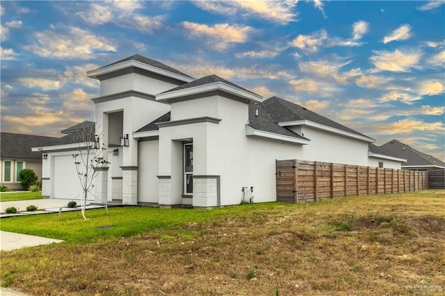 property exterior at dusk featuring a yard and a garage