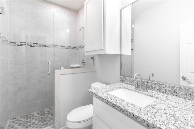 bathroom featuring vanity, a shower with shower door, and toilet