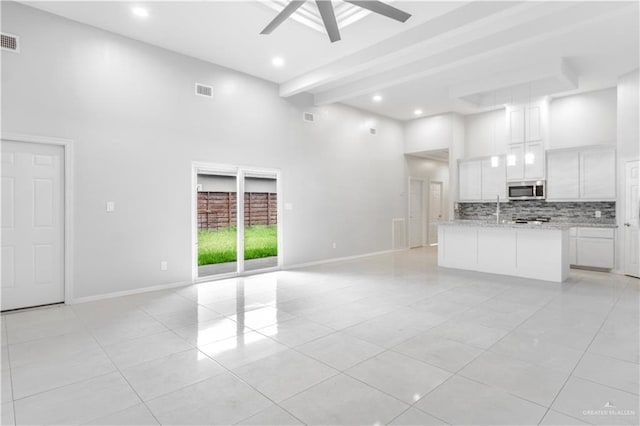 kitchen featuring beamed ceiling, light tile patterned floors, white cabinetry, and light stone countertops