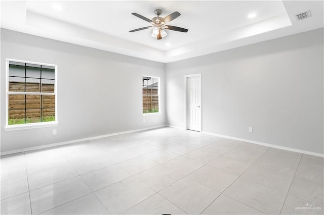 tiled spare room featuring ceiling fan and a raised ceiling