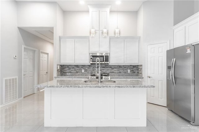 kitchen featuring light stone counters, white cabinetry, stainless steel appliances, and decorative light fixtures