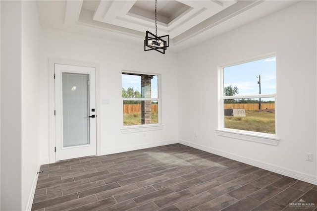 unfurnished dining area with a notable chandelier, dark hardwood / wood-style flooring, and a tray ceiling