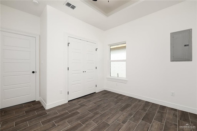 unfurnished bedroom featuring electric panel, a closet, and dark hardwood / wood-style flooring