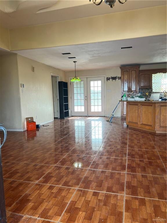 kitchen featuring an inviting chandelier, french doors, hanging light fixtures, dark hardwood / wood-style floors, and tasteful backsplash