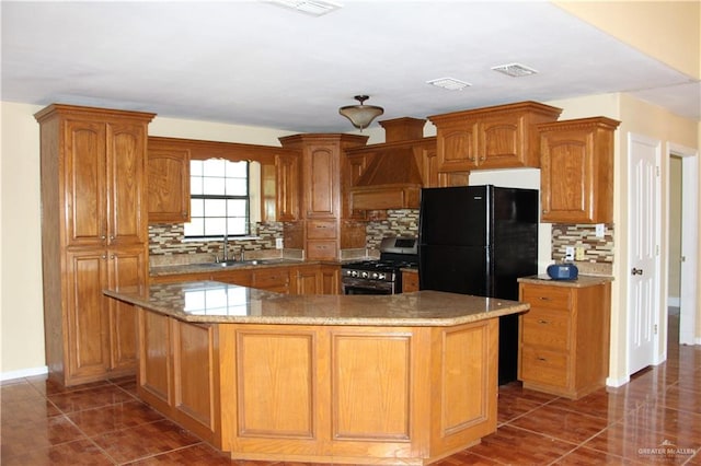 kitchen featuring decorative backsplash, gas stove, a kitchen island, and black fridge