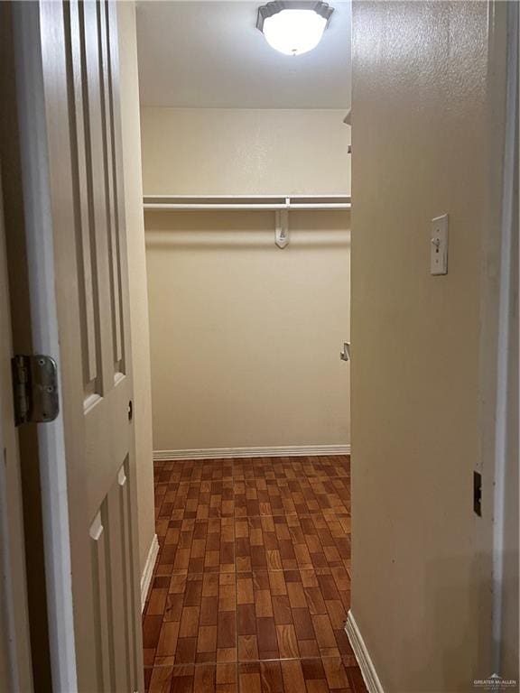 walk in closet with dark hardwood / wood-style floors