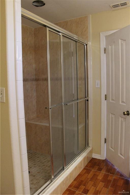 bathroom with hardwood / wood-style flooring and walk in shower