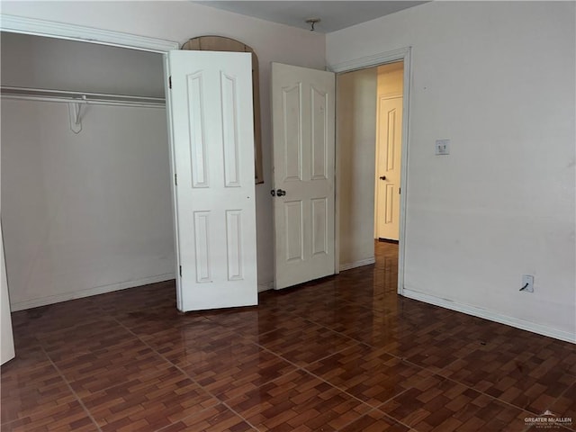 unfurnished bedroom with dark hardwood / wood-style flooring and a closet