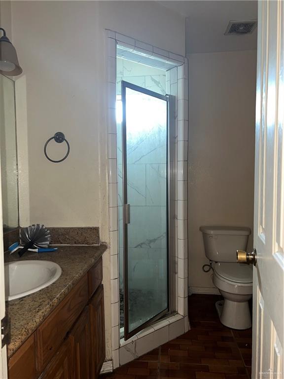 bathroom with vanity, hardwood / wood-style flooring, toilet, and a shower with door