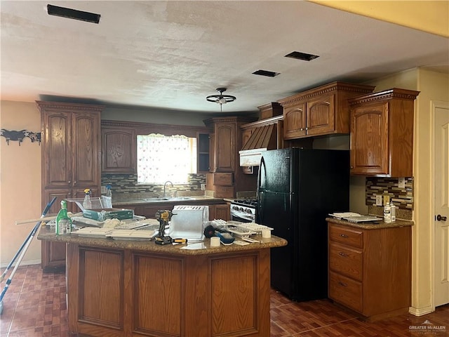 kitchen featuring a center island, black refrigerator, tasteful backsplash, and gas range