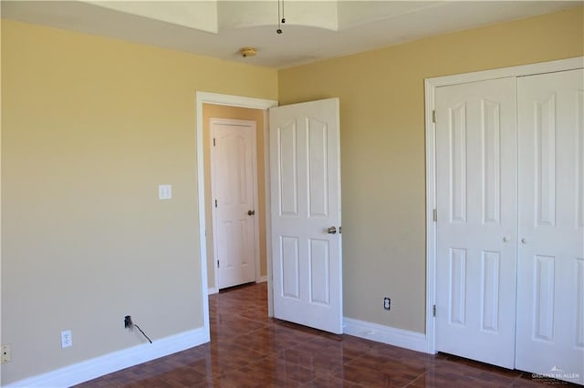 unfurnished bedroom featuring a closet and dark tile patterned flooring