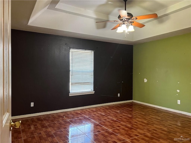 spare room featuring ceiling fan, dark hardwood / wood-style flooring, and a tray ceiling