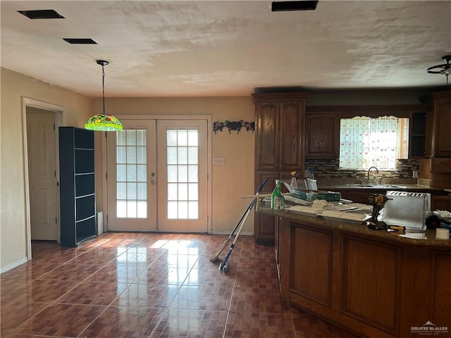 kitchen with french doors, dishwasher, sink, pendant lighting, and decorative backsplash