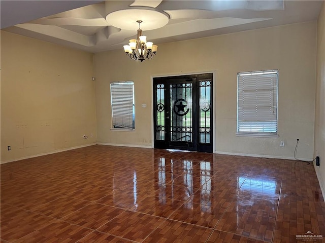 foyer entrance with dark hardwood / wood-style floors, a tray ceiling, and a chandelier