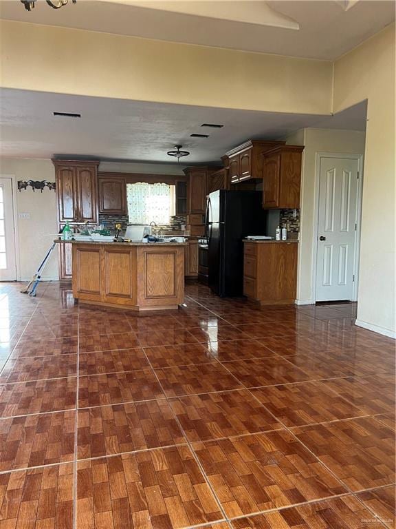 kitchen with tasteful backsplash, black fridge, dark hardwood / wood-style floors, and stainless steel stove