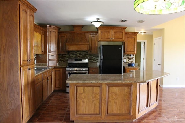 kitchen with stainless steel stove, black fridge, tasteful backsplash, and a kitchen island