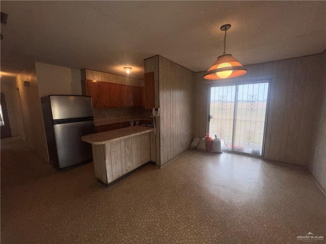 1116 S Orange St, Mercedes, TX 78570 - kitchen featuring freestanding refrigerator, a peninsula, pendant lighting, and brown cabinetry