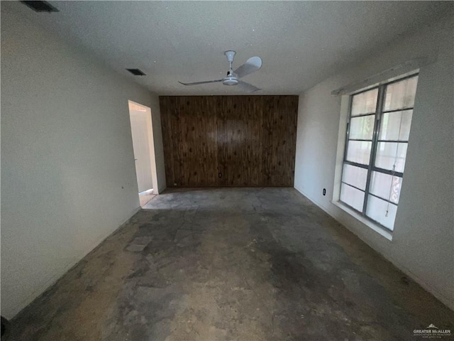 1116 S Orange St, Mercedes, TX 78570 - spare room featuring unfinished concrete floors, a ceiling fan, and wood walls