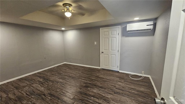 basement with a wall unit AC, ceiling fan, and dark wood-type flooring