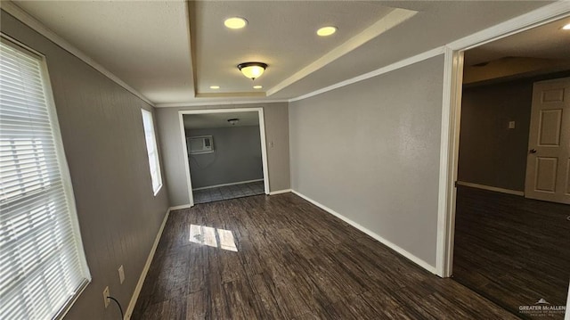 unfurnished room with a raised ceiling, dark hardwood / wood-style flooring, ornamental molding, and an AC wall unit