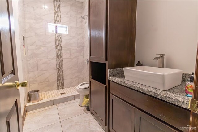 bathroom featuring a tile shower, vanity, toilet, and tile patterned floors