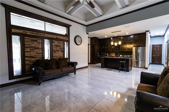 living room with crown molding, beamed ceiling, a high ceiling, and ceiling fan