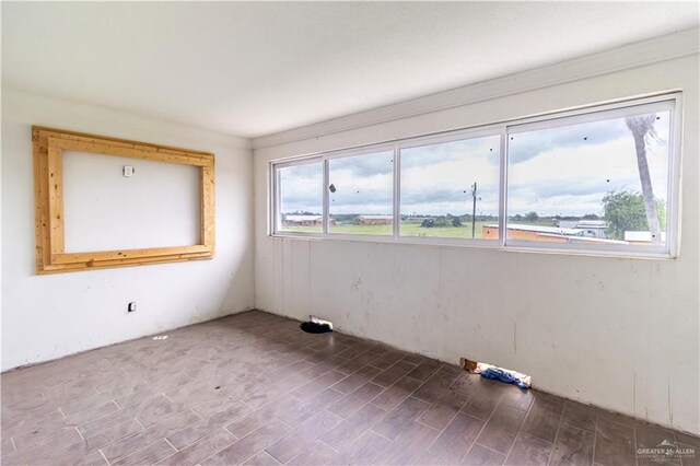 empty room with dark hardwood / wood-style flooring and ornamental molding