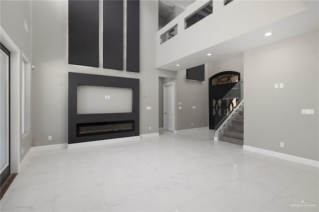 unfurnished living room featuring a towering ceiling