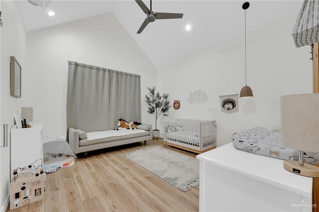 bedroom featuring ceiling fan, wood finished floors, high vaulted ceiling, a crib, and recessed lighting