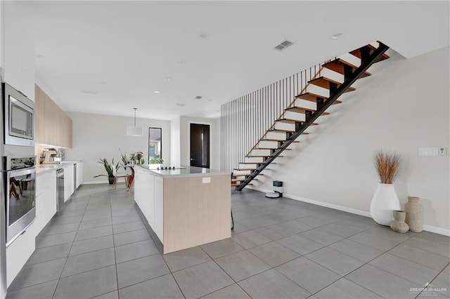 kitchen featuring modern cabinets, a center island, light countertops, light tile patterned floors, and stainless steel appliances