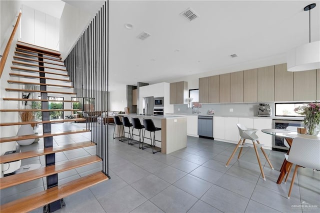kitchen with visible vents, modern cabinets, a center island, light countertops, and stainless steel appliances