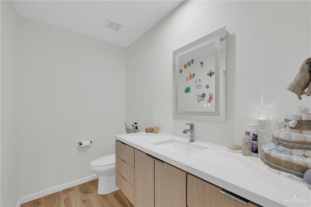 bathroom featuring visible vents, vanity, wood finished floors, toilet, and baseboards