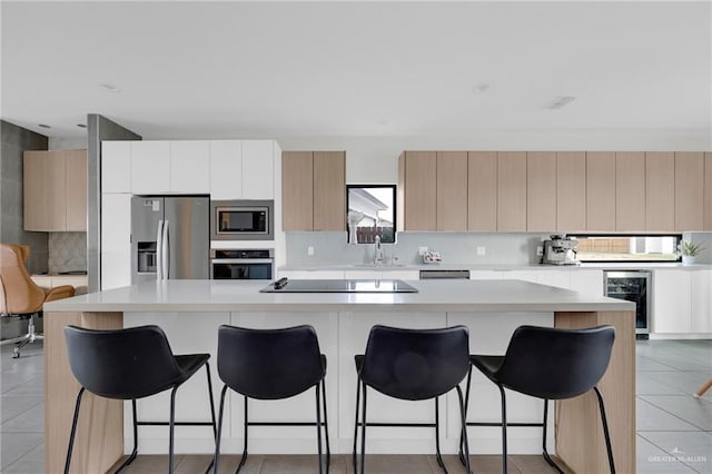 kitchen with light countertops, beverage cooler, appliances with stainless steel finishes, and a sink